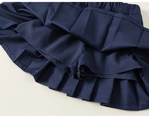 Detailed view of navy blue pleated skirt featuring built-in safety shorts and elastic waist