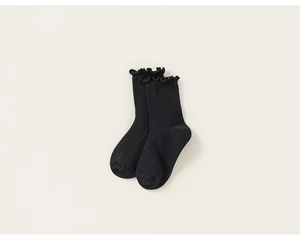 Detail of black cotton blend ribbed socks featuring elegant lettuce edge trim and soft texture