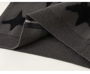 Detail of dark grey knit cardigan with black stars, ribbed hem and silver metal zipper