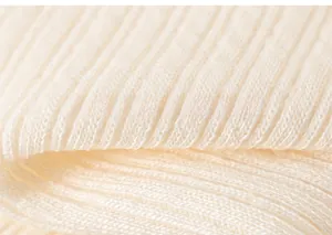 Close-up macro view of soft cream ribbed knit fabric texture for children's clothing set