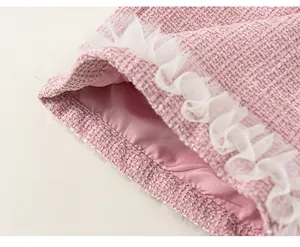 Detail of light pink tweed fabric with glitter threads and white mesh ruffle trim