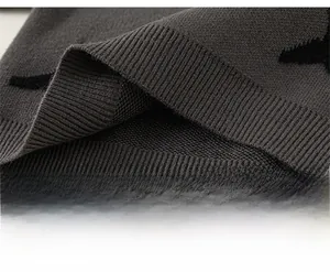 Detailed close-up of dark grey knitted kids sweater hem with black star jacquard patterns