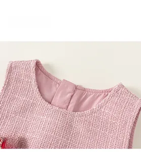 Close-up of pink tweed girl's dress fabric with a plaid bow detail and round collar