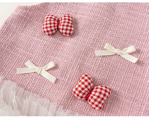 Detail of pink tweed girl's outfit with bow decorations and white mesh splicing