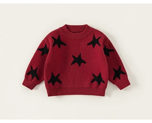 Macro detail of wine red knitted sweater featuring black stars and ribbed cuffs
