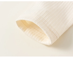 Detail of the cream rib-knit sleeve cuff showing fine texture and clean stitching