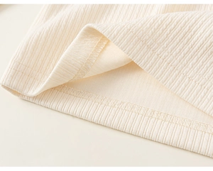 Detailed macro view of the cream ribbed knit fabric showing neat stitching and overlock seams