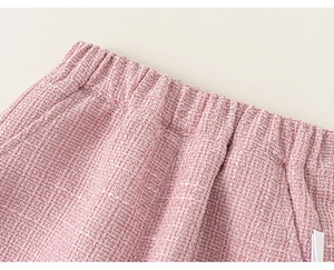 Detailed close-up of pink tweed fabric texture and elastic waistband of girls clothing