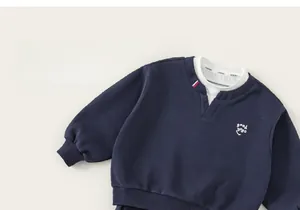Détail du sweat-shirt enfant bleu marine avec faux col et broderie logo souriant