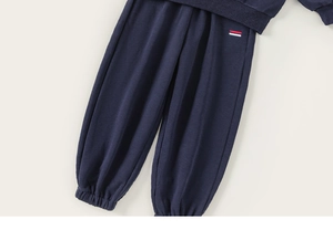Détail d'un pantalon de jogging bleu marine pour enfant avec logo brodé et chevilles