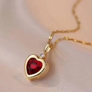 Elegant gold titanium necklace featuring a red heart gemstone and a clear zircon stone