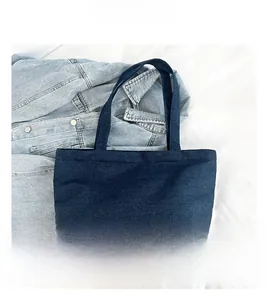 Detail view of durable navy denim fabric texture and sturdy wide handles on the tote bag