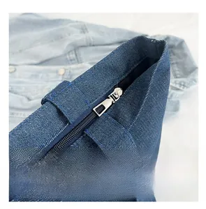 Close-up of smooth silver metal zipper on the deep blue denim tote bag opening