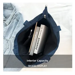 Top view of spacious interior of dark blue denim tote bag with metal zipper and books