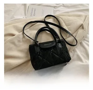 Detailed macro view of black quilted leather texture and adjustable shoulder strap on bag
