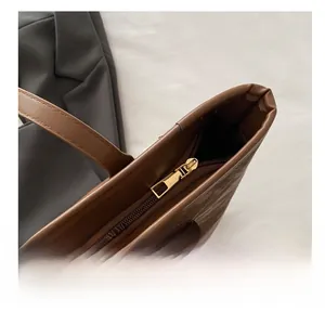 Detail of smooth golden metal zipper on a dark brown vintage textured leather tote bag