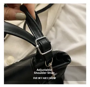 Close-up of adjustable black leather strap with silver buckle on a crossbody bag