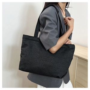 Detailed view of a large black denim tote bag on a model for casual daily use