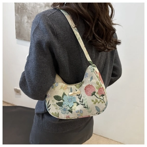 Detailed view of floral jacquard crescent bag with golden metal plate on model