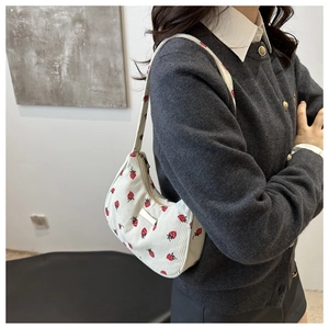 Detail of white corduroy shoulder bag with dense red strawberry embroidery and metal zipper