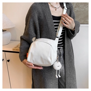 Lifestyle shot of white crossbody bag with orange label and plush eye charm detail