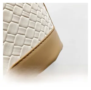 Detail view of woven white leather texture and smooth khaki leather stitching on the handbag