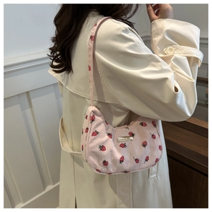 Detail of pink corduroy shoulder bag featuring red strawberry patterns and metal logo