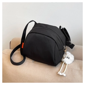 Detail of black crossbody bag with fashion tag and cute white plush mascot accessory