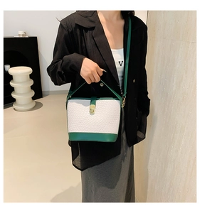 Close-up of white croc-embossed bucket bag with dark green trim and golden metal lock