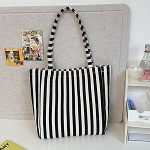 Detailed view of black and white vertical striped canvas tote bag with long shoulder strap