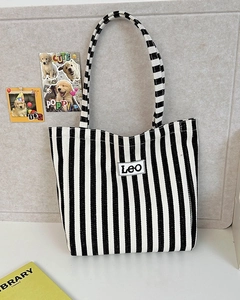 Detail of canvas tote bag with black and white vertical stripes and Leo brand tag
