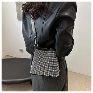 Sac seau noir chic à strass avec bandoulière chevron porté par un mannequin stylé