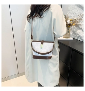 Detail showing the white woven leather texture and dark brown trim of the bucket bag
