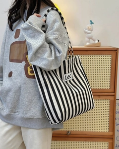 Detail of blue and white striped canvas tote bag with woven shoulder strap and Leo tag