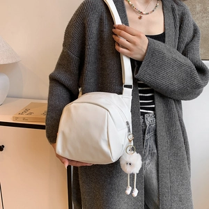 Minimalist white leather crossbody bag with broad strap and plush doll charm decoration