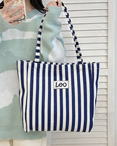 Detail of blue and white striped canvas tote bag with Leo patch on casual shoulder strap