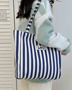 Detail view of large canvas tote bag with blue and white stripes and Leo patch