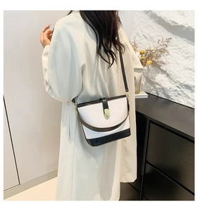 Detail of the black and white bucket bag featuring snake pattern embossing and gold metal buckle