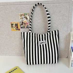 Detail of blue and white striped canvas tote bag with Leo logo on a desk setting
