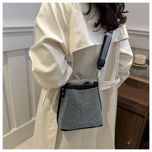 Détail du sac seau à strass scintillants avec bandoulière tissée sur un trench beige