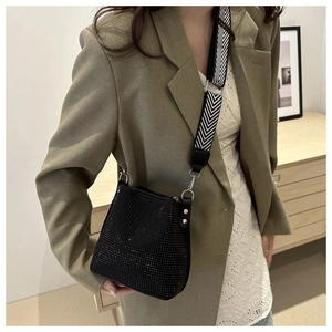 Détail du sac seau en strass noirs avec une large bandoulière tissée géométrique