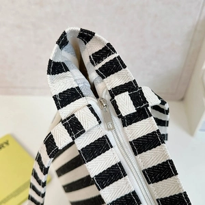 Macro shot of the silver metal zipper closure on the striped canvas tote bag detail