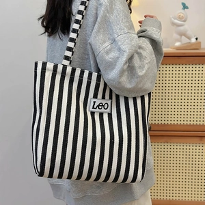 Close-up of canvas tote bag with black and white stripes and Leo leather patch