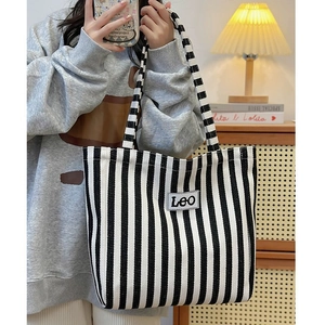 Detail of blue and white striped canvas tote bag with Leo patch shown on shoulder