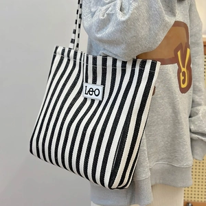 Detail of canvas tote bag featuring black and white vertical stripes and LeO logo patch