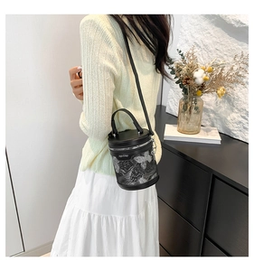 Detailed close-up of a black lace bucket bag with leather accents and zip closure