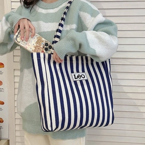 Close-up of blue and white striped canvas tote bag featuring a square LEO fabric patch