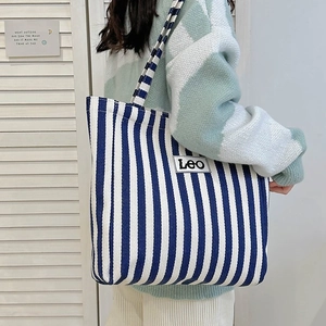 Detail of blue and white striped canvas tote bag with Leo woven label and shoulder strap