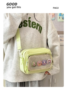 Detail view of mint green nylon crossbody bag with transparent mesh pocket and badges