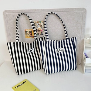 Detailed macro view of blue and white striped canvas tote bags with Leo patch embroidery